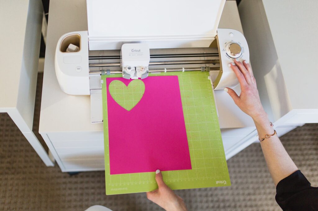 person putting colored paper on a cutting machine